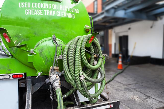 a technician pumping a grease trap in a commercial building in Harwood Heights